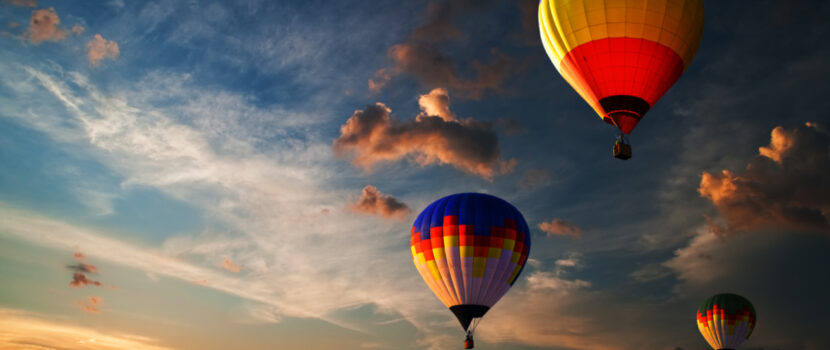 Three colourful hot air balloons flying at sunrise