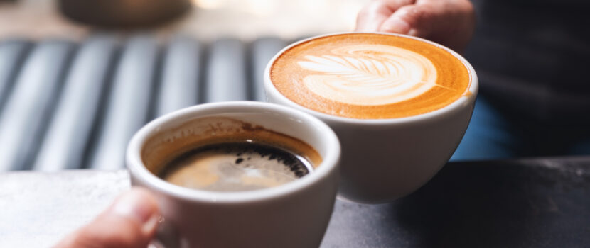 Close up of two people holding coffee cups in a cafe