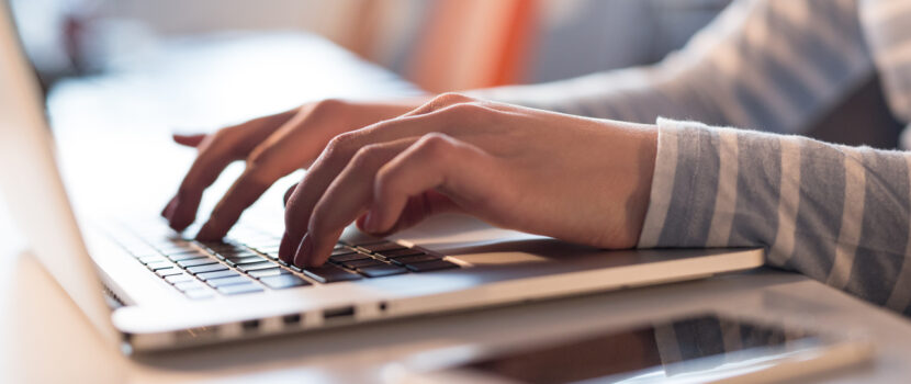 A young woman typing on a laptop in an office space.