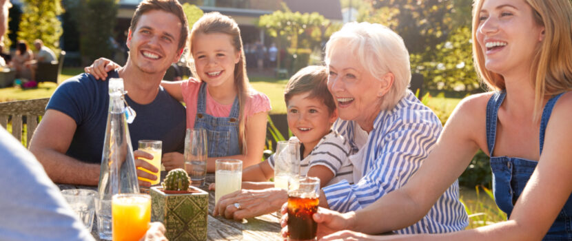 A smiling family sitting around a garden table.