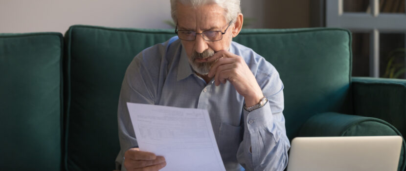 An older man reviewing some paperwork at home.