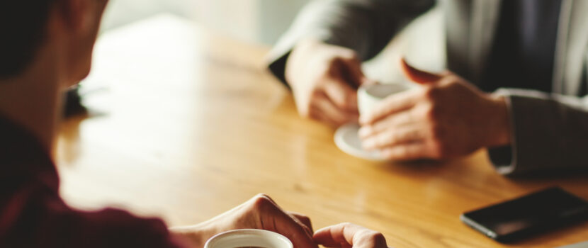 Two men talking over coffee in a café.