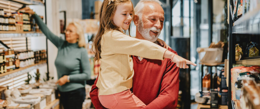 A grandfather grocery shopping with his granddaughter.