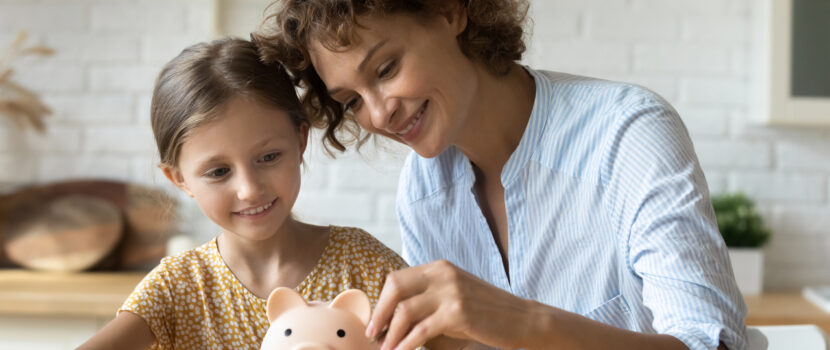 Mother and daughter saving in a piggy bank