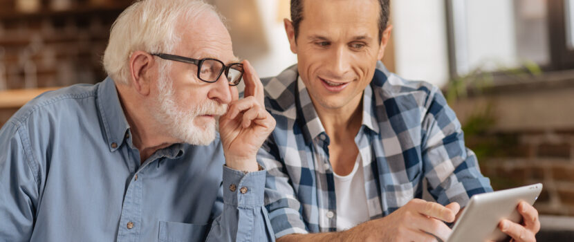 Young man showing his elderly father something on a tablet