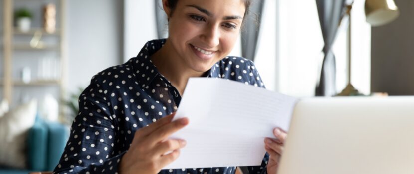 A woman smiling as she looks at paperwork.